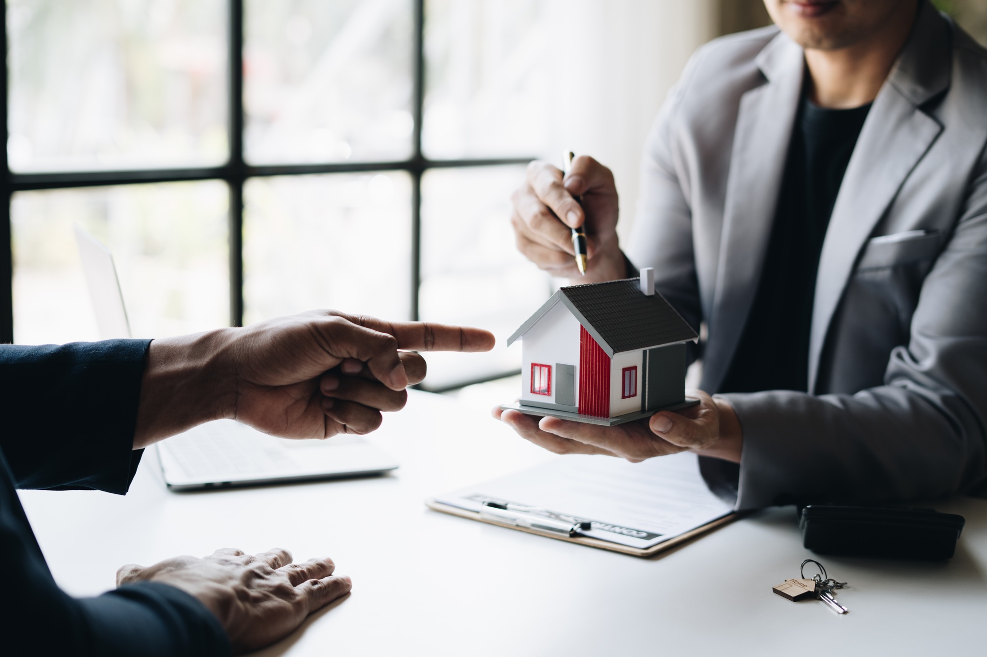 Real estate agent holding house key to his client after signing contract,concept for real estate.